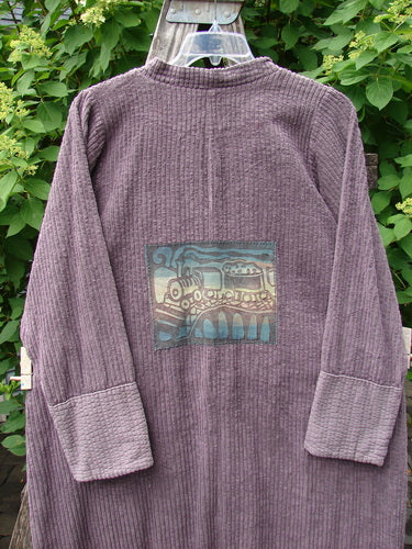 Barclay Patched Chenille Straight Coat Aubergine Dust Size 1 features a long-sleeved, corduroy-textured design with a steam locomotive appliqué on the back, displayed against foliage.