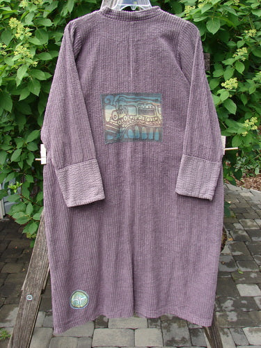 Barclay Patched Chenille Straight Coat in Aubergine Dust, featuring a back landscape patch, metal buttons, and a canvas pocket, hanging outdoors.