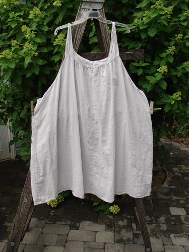 Barclay Batiste Banded Collar Slip Dress Unpainted Natural Size 1 displayed on a wooden stepladder outdoors, showcasing its sleeveless smock-style with a wide rounded neckline and swingy lower hem.