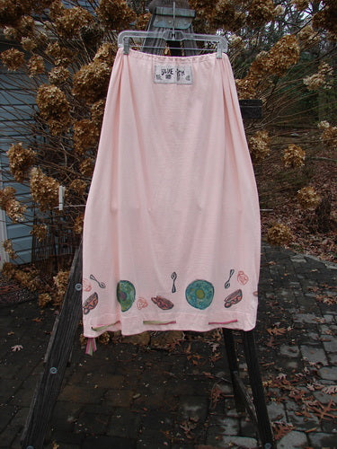 1992 Buttonloop Skirt Breakfast Diner Sea Shell OSFA: A pink skirt with a drawcord waist and button holes, hanging on a rack, showcasing its unique hemline and vintage design.