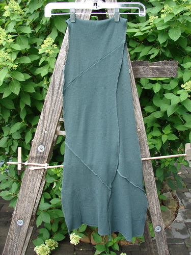 Barclay Thermal Patched Curvy Scarf Army Forest OSFA with diagonal seams and scalloped hem, displayed on an outdoor wooden frame against lush greenery; embodies BlueFishFinder's vintage, expressive fashion ethos.