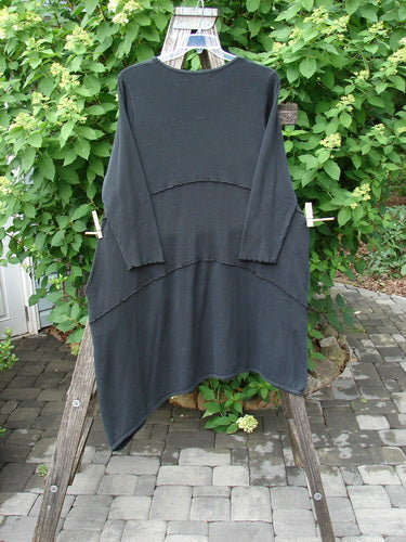 Barclay Thermal Exterior Stitch Three Tier Dress in Unpainted Black, Size 2, displayed draped over a wooden stepladder, showcasing its asymmetrical hem and long sleeves.