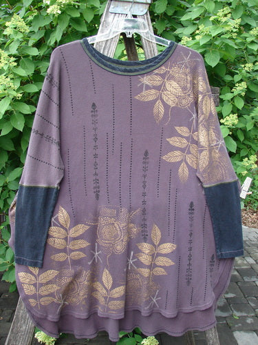 Barclay Thermal Contrast Revival Top Metallic Leaf Brum OSFA hangs on a wooden trellis, showcasing muted purple fabric with mustard floral patterns, contrasting cuffs, and neckline, ideal for fall layering.