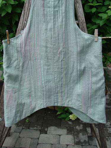 Barclay Linen Side Pocket Apron Jumper Verticals Sage Size 0 features faint pastel stripes, two large front pockets, and adjustable shoulder straps, hanging on a clothesline.