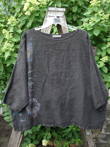 Barclay Linen Lantern Boxy Top Side Floral Black Size 1, hangs on a ladder outdoors, showcasing its loose cut, boat neckline, and hand-painted floral motif, embodying Bluefishfinder's creative and vintage aesthetic.