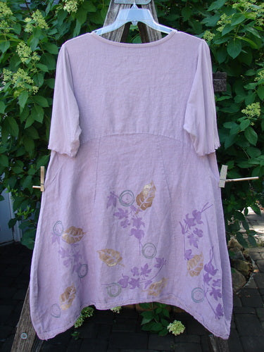 Barclay Linen Lace Blooming Tunic Dress Leaf Vine Lavender Size 0, featuring a cross-over neckline and lace-trimmed hem, hangs on a clothesline. The dress showcases floral motifs, embodying vintage elegance.