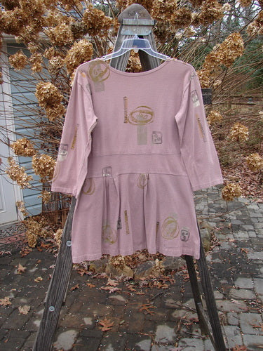 1991 Workshop Dress Spin Stone Currant OSFA displayed on a wooden stand with pleats and a drop waistband, showcasing a tailored fit with a scooped neckline and slightly shorter sleeves.