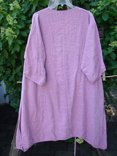 Barclay Linen High Vent Venetian Dress Center Leaf Peony Rose Size 1: A lavender tunic with dropped shoulders, high side vents, and a softly dipped V neckline, displaying a graceful drape against greenery.