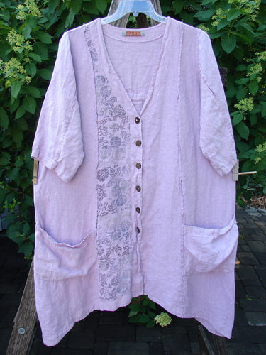 Barclay Linen Double Tie Back Jacket Single Garden Row Pink Cloud Size 1, featuring a loose fit, V-neck, elbow-length sleeves, large patch pockets, and a floral print detail, hanging outdoors.