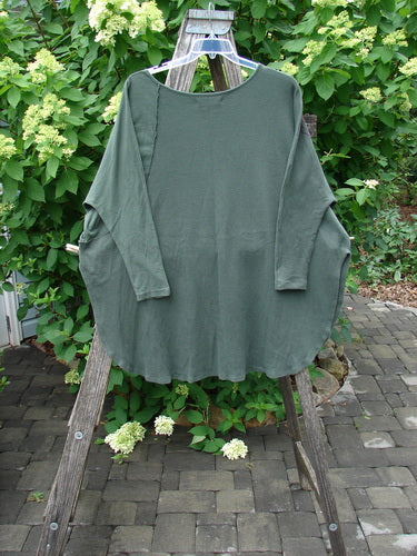 Barclay Thermal Monte Verde Vented Tunic Linear Blend Army OSFA displayed on a hanger, features a scooped neckline, side vents, and ribbed sleeve accents, set against a patio backdrop.