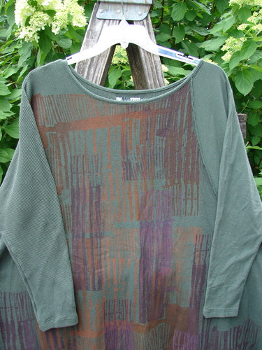 The Barclay Thermal Monte Verde Vented Tunic Linear Blend Army OSFA features a muted green, loose-fit design with abstract vertical stripes, highlighting mixed fabrics and side vents, perfect for creative expression.