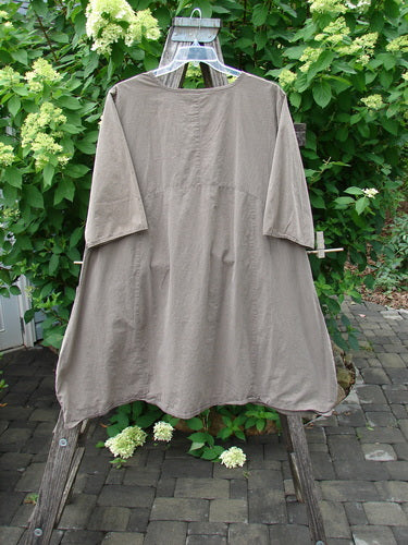 Barclay Percal Urchin Dress Climbing Garden Stripe Rock Size 0, a loose tunic-style garment draped over a wooden stepladder, highlighting its relaxed fit and sophisticated design amidst a serene patio backdrop.