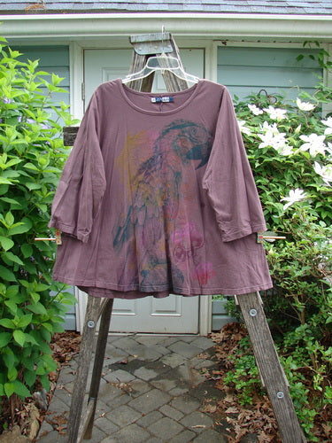 Barclay Three Quarter Sleeved A Line Tee features a rolled neckline and unadorned back, showcasing a parrot theme. Ideal for expressing individuality, this mid-weight organic cotton piece reflects BlueFishFinder's unique style.