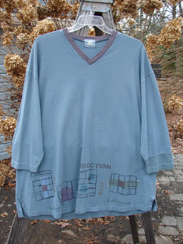 2000 V Neck Grid Top Direction Travel Puddle Size 1 displayed on a hanger, showcasing its A-line shape, single cuff, V neckline, and slightly rounded bottom sweep with tiny vented sides.