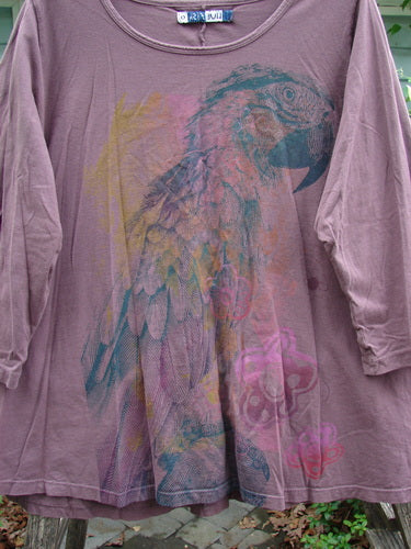 Barclay Three Quarter Sleeved A Line Tee, single parrot theme in fig, showcases a rounded, rolled neckline and flat edgings, highlighting its mid-weight organic cotton fabric and A-line silhouette.