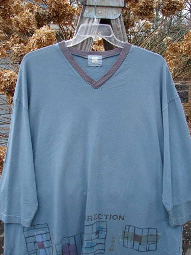 2000 V Neck Grid Top Direction Travel Puddle Size 1 displayed on a hanger, showcasing its organic cotton fabric, V neckline, and unique paint details with a slightly rounded bottom sweep.