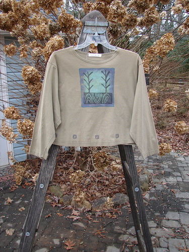 1996 Boxy Tee Top Twig Tree Bottlecap Size 2, featuring long sleeves, a blue square patch, and twig tree painting, displayed on a hanger.
