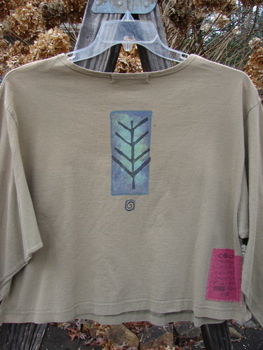 1996 Boxy Tee Top Twig Tree Bottlecap Size 2 features a tan shirt with a blue twig tree design, slightly wider neckline, tiny vented sides, and a gently rolled neckline, made from organic cotton.