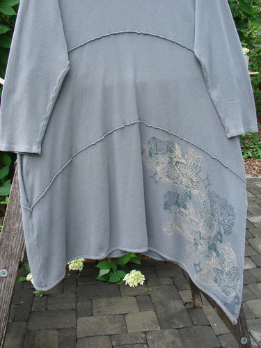 Barclay Thermal Exterior Stitch Three Tier Dress, Forest Friend Grey Day, Size 2, draped on a wooden bench, showcasing its asymmetrical hem, layered seams, and subtle floral print on the lower panel.