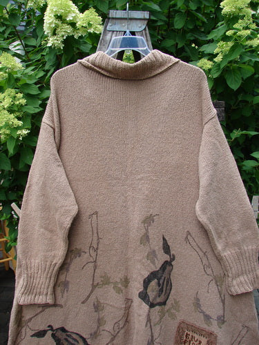 1998 Cotton Knit Canyon Cardigan Sweater Coat Pear Harvest Aspen OSFA: This vintage taupe knit sweater-coat features a shawl collar, ribbed cuffs, vine pattern, oversized button, angled pockets, and an A-line shape against a green foliage backdrop.