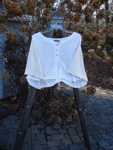 Barclay NWT Cotton Sleeved Crop Drawcord Top displayed on a hanger with three-button front, three-quarter length sleeves, and vertical pull cord accents in a natural outdoor setting.