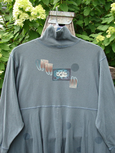 1996 Enchantment Dress Polka Path Mirror Size 2 features a muted-teal/gray long-sleeve pullover with a mock neck, abstract chest graphic, and faint water spots, hanging against a garden backdrop.