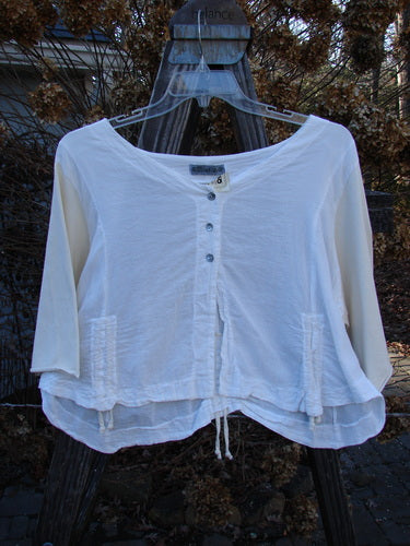 Barclay NWT Cotton Sleeved Crop Drawcord Top displayed on a hanger outdoors, showcasing its three-quarter length sleeves, wider V-neckline, and vertical pull cord accents.