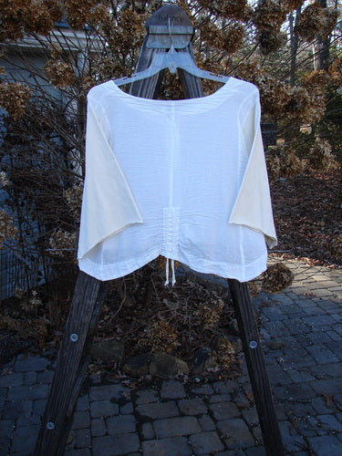 Barclay NWT Cotton Sleeved Crop Drawcord Top on a wooden ladder, featuring a three-button front, three-quarter length sleeves, and vertical pull cord accents, showcased outdoors.