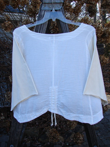 Barclay NWT Cotton Sleeved Crop Drawcord Top Unpainted White Creme Size 2 displayed on a swing, showcasing its three-button front, wide V neckline, and vertical pull cord accents.