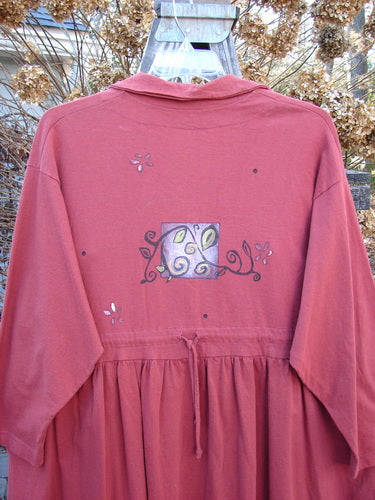 1997 Hearth Peplum Button Duo Vines Brick Size 2: Red jacket featuring a deep V-neckline, oversized pearl-like buttons, empire waist seam, gathered hemline, and garden vine-themed painting, worn by a person.