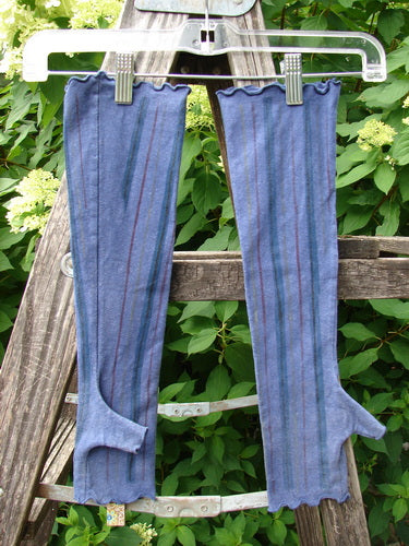 Barclay Cotton Lycra Hemp Fingerless Glove Stripe Royal Orchid OSFA, displayed on a plastic hanger, features blue striped knit fabric with a thumb hole, hanging outdoors against a lush green backdrop.