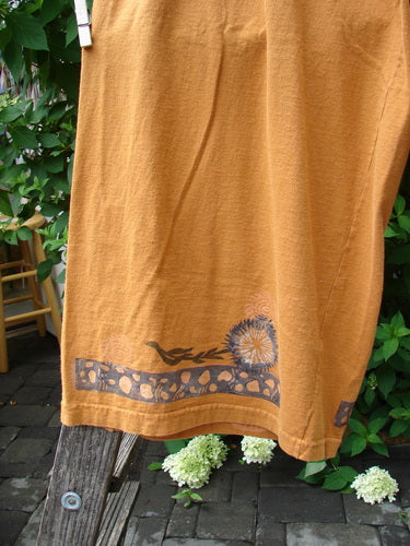Mustard-yellow 1994 Banjo Pant Dandelion Breeze Oro Size 2 with a dark dandelion and vine motif hem, hanging to dry on a wooden fence, evoking vintage Blue Fish Clothing's creative spirit.
