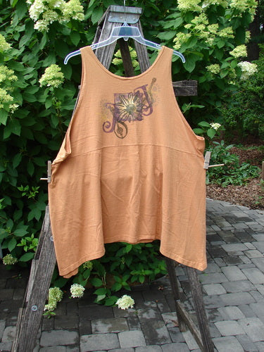 1994 Short Simple Smock Double Daisy Oro Size 1: A loose-fit, sleeveless tank top with a floral print across the chest, hanging outdoors amidst leafy shrubs on a patio, showcasing its flowing design and rounded neckline.