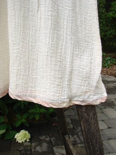 1998 Gauze Under Skirt Unpainted Cloud Size 2 features a cream, crinkled cotton gauze fabric with pink silk ribbon hem, hanging gracefully over a wooden frame, embodying vintage elegance from Bluefishfinder.com.