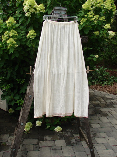 Vintage 1998 Gauze Under Skirt Unpainted Cloud Size 2 draped over a wooden ladder, showcasing its flowing A-line shape and delicate silk ribbon hem, embodying Bluefishfinder.com's unique vintage style.