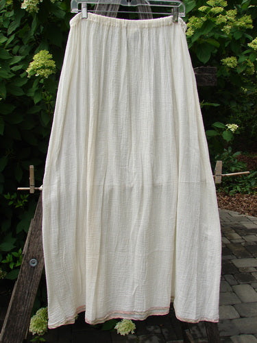 1998 Gauze Under Skirt Unpainted Cloud Size 2, ankle-length cotton skirt with an elastic waistband, hanging outdoors. Features a full A-line shape with a silk ribbon hem, swaying gently.