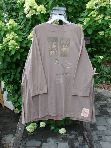 1999 Silverware Top Reverse Dining Riverbed OSFA draped on wooden stand outdoors, featuring starburst motifs, silverware graphics, and a woven patch, set against lush greenery and blooms.