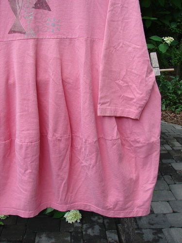 1997 Brenton Dress Two Fish Tulip Size 2: Loose-fitting pink vintage dress with a gathered skirt, metallic chest graphic, round neckline, and deep side pockets, exemplifying Blue Fish Clothing's creative vintage style.