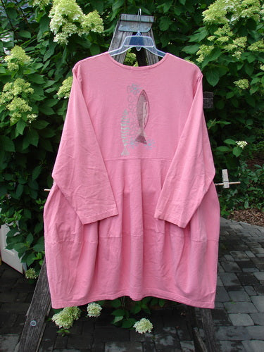 1997 Brenton Dress Two Fish Tulip Size 2 features a loose-fitting, long-sleeved design with a stylized fish graphic, rounded neckline, dropped yoke waist, and deep side pockets, hanging on a wooden bench.