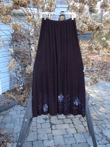 1999 Acetate Streamer Moonbeam Duo Key Deep Burgundy Size 1 showcasing a long purple skirt with a flowing A-line shape and delicate lettuce edging, hanging on a clothesline outdoors.