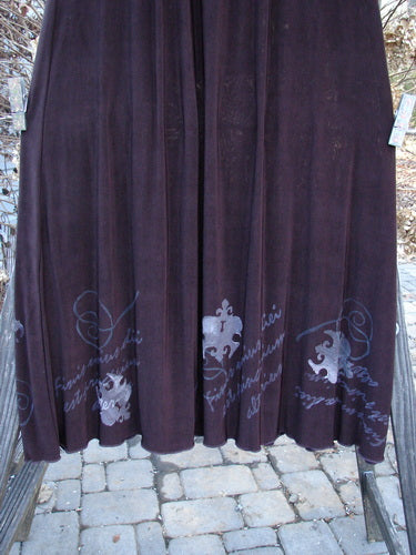 1999 Acetate Streamer Moonbeam Duo Key Deep Burgundy Size 1: A long purple skirt with writing, paired with a detailed vest featuring a silk tie closure and unique lettuce edging.