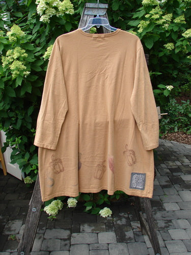 1998 Vegetable Tunic Top Bountiful Garden Ochre Size 2, displayed on a wooden ladder, features a knee-length, camel-colored design with long sleeves, a softly scooped neckline, and printed motifs along the hem.