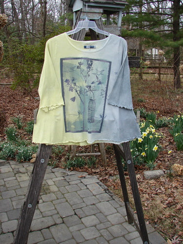 Barclay Three Quarter A Line Tee Garden Friend Sunshine Size 0 displayed on a rack, featuring a birdcage and flowers motif on organic cotton with a rounded neckline and flat edgings.