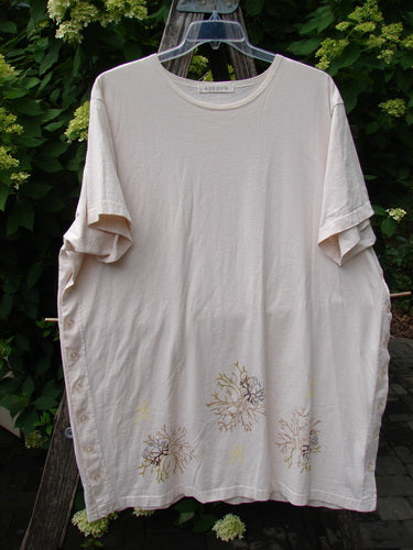 1997 Mauritius Top Sea Coral Powder OSFA, features a loose-cut, cream-colored design with a round neckline, short rolled sleeves, side buttons, and a floral motif at the hem, ideal for summer wear.