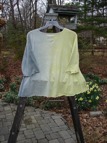 Barclay Three Quarter A Line Tee Garden Friend Sunshine Size 0 on a wooden stand, featuring a rounded, rolled neckline and flat edgings, displayed in an outdoor setting.