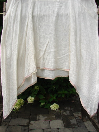 1998 Gauze Over Dress Silk Ribbon Unpainted Chalk Size 2 displayed outdoors, showing its lightweight cotton gauze and hand-dyed silk rainbow ribbon edging, draped to highlight versatile, airy design.