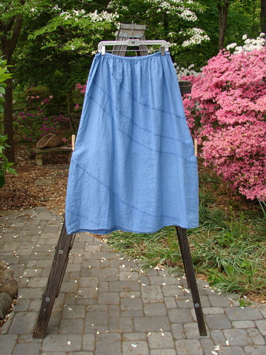 Barclay Linen Diagonal Skirt Unpainted Skylark Size 2 displayed on a rack, showcasing its pleated design and diagonal stitchery, ideal for creating a unique and special look.