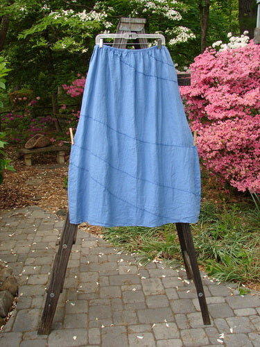 Barclay Linen Diagonal Skirt Unpainted Skylark Size 2 hanging on a clothesline, showcasing its diagonal stitchery and widening length.