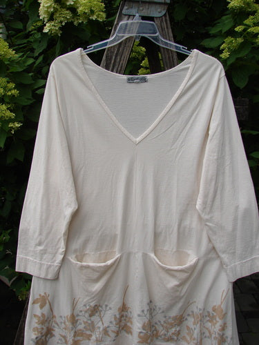 Barclay Deep V Neck Rear Banded Pocket Tunic Morning Garden Dew Size 1, featuring three-quarter sleeves and hip-height pockets, hangs outdoors showcasing a subtle floral print along the hem.