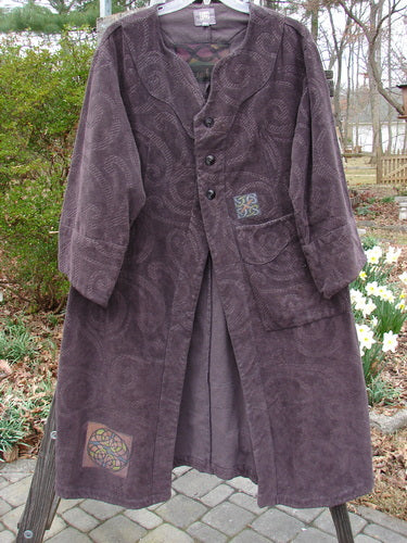 2000 Patched Upholstery Diwmach Coat Celtic Time Aubergine Size 0 displayed on a hanger outdoors, showcasing its detailed damask paisley pattern, colorful patches, and vintage buttons.